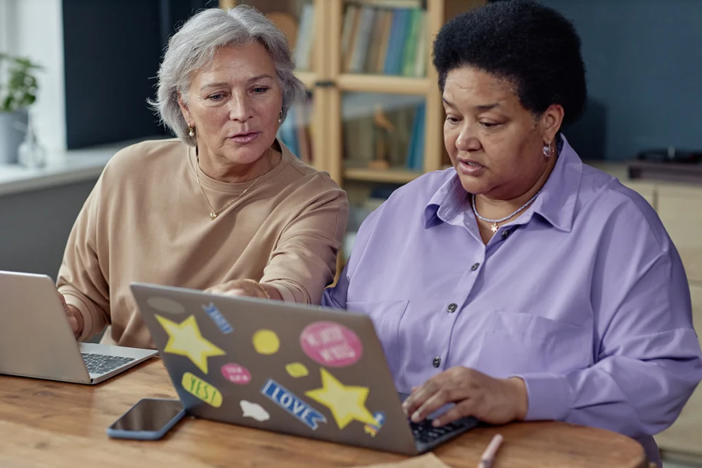 Portrait of two senior women using laptops