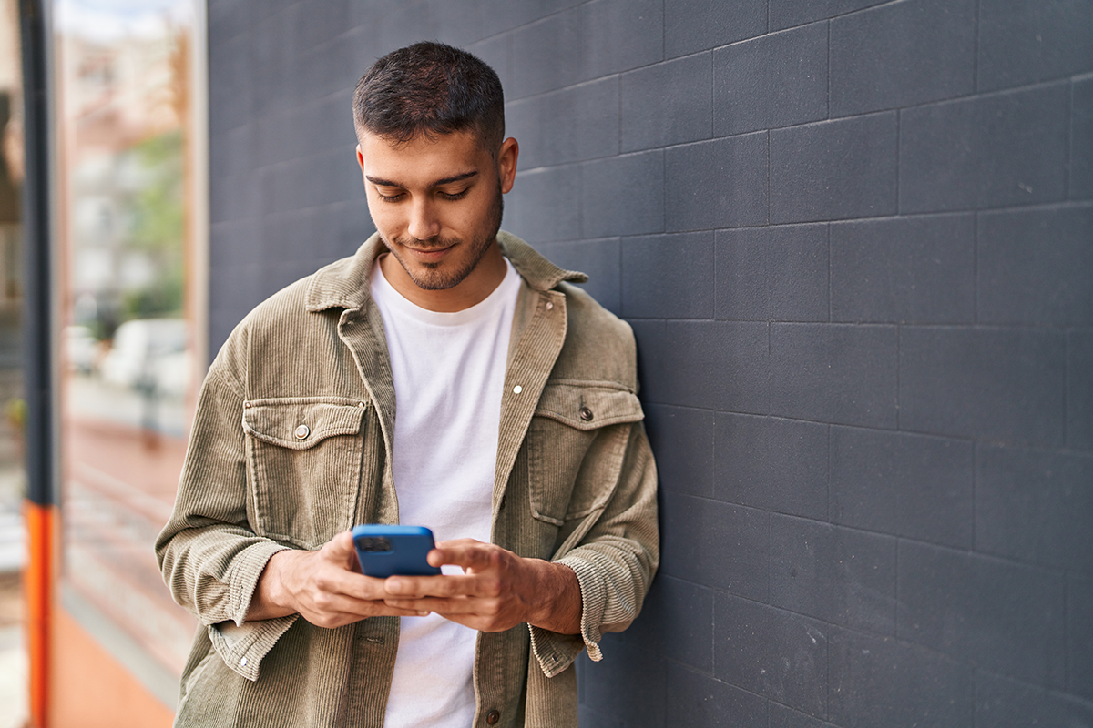 Student looking at phone, leaning against wall