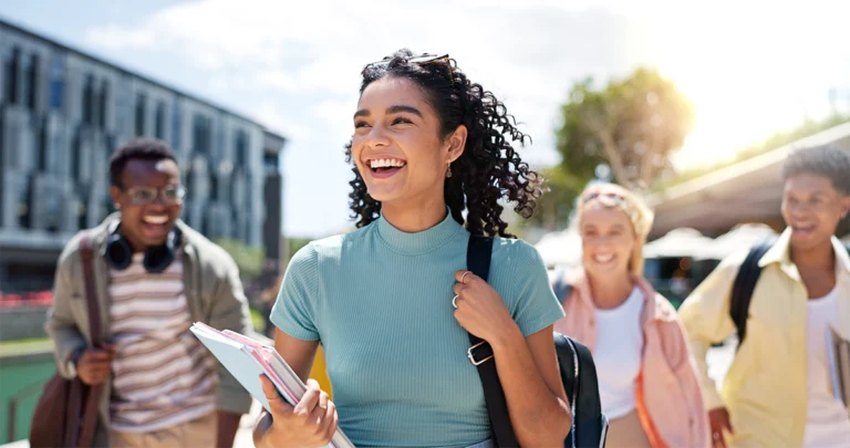 A group of gen z students walking outside on a college campus.